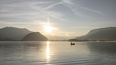 Sonnenuntergang hinter dem Wolfgangsee mit einem Mann auf einem Fischerboot