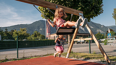 Zwei Kinder schaukeln am Spielplatz beim Campingplatz Paradiescamping Wolfgangsee